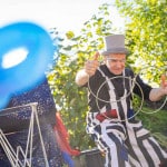 Zaubertricks mit vielen großen silbernen Ringen. Kinderzauberer Michael in Aktion bei einem Kindergeburtstag. Ein Mädchen steht staunend neben dem Zauberer