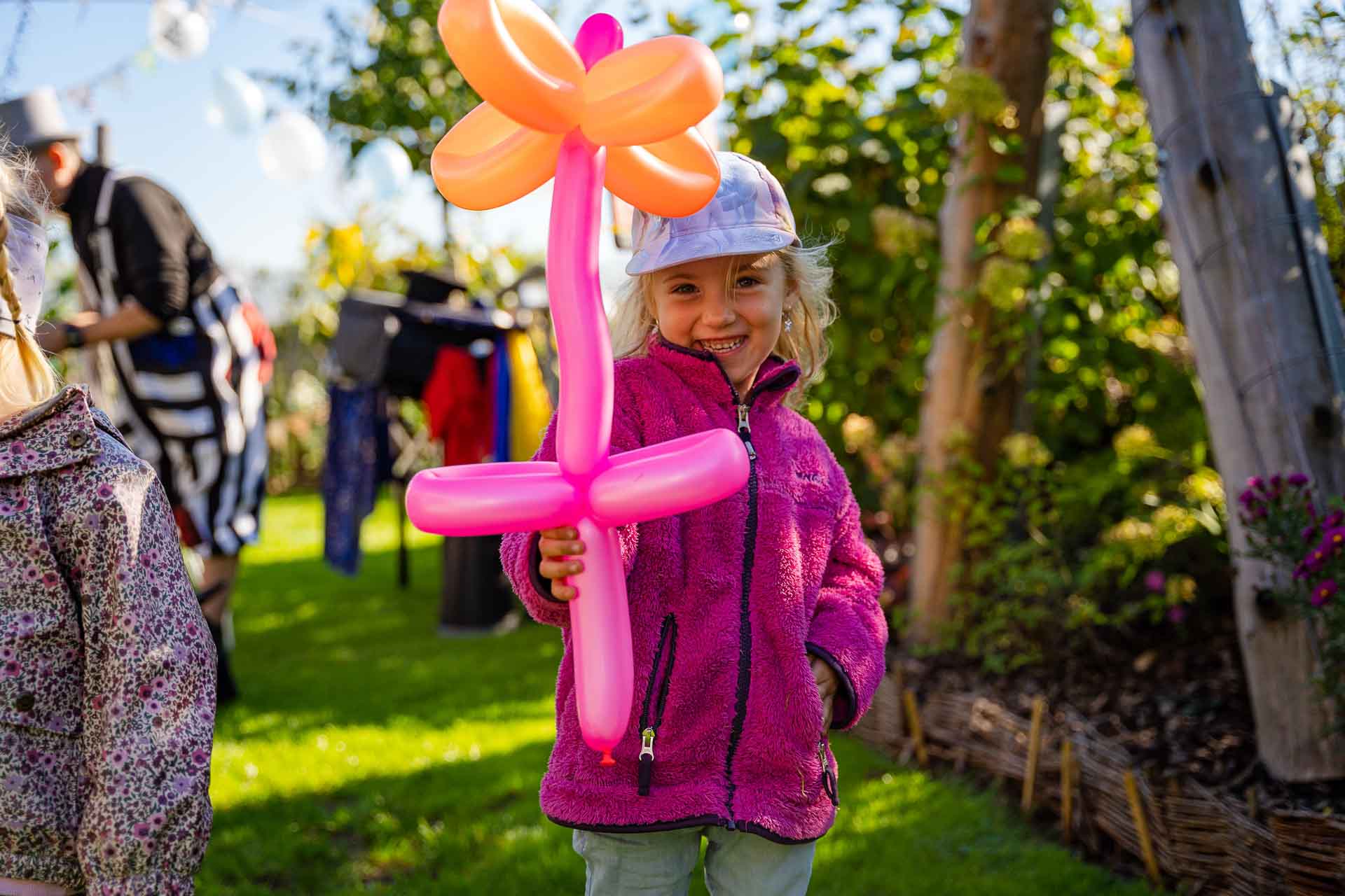 Lachendes Mädchen mit einer Blume, die aus Luftballons angefertigt wurde von Ballonkünstler und Kinderzauberer Michael aus München